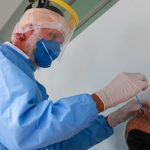 profissionais de saúde usando epi coloca cotonete no nariz de homem para testar para coronvírus