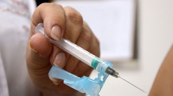 Uma mão segura uma seringa de vacina próximo a um braço. A prefeitura de Florianópolis vai iniciar a campanha de vacinação contra a influenza.