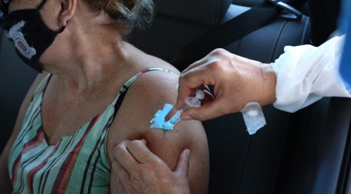 Mulher com regata colorida usa máscara e recebe por meio de uma seringa a vacina, aplicado por um profissional da saúde. No fim de semana, Florianópolis aplicou mais de 5 mil segundas doses.