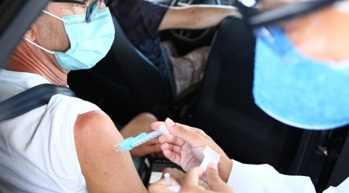 profissional de saúde aplica dose da vacina no braço de pessoa dentro do carro - vacinação de 64 anos contra coronavírus em Florianópolis