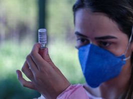 Após três meses de campanha de imunização, 11% dos grupos prioritários está vacinado mulher usando máscara olha para ampola ao retirar dose de vacina - três meses de vacinação em sc