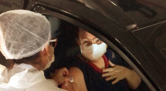 idosa usando máscara é vacinada dentro de carrro por profissional de saúde usando EPI - São José amplia a vacinação para os idosos com 67 anos ou mais