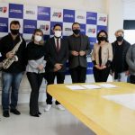 grupo de pessoas em pé usando máscara posa para foto (representantes da prefeitura e da orquestra) - são josé assina com OSSCA