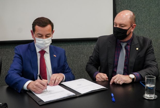 eron giordani e marudo de nadal usam máscara enquanto o primeiro assina documento de repasses aos municípios