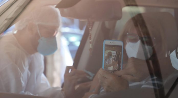 A foto mostra dentro de um veículo um profissional de saúde aplicando uma dose de vacina em um paciente que está sentado dentro do carro, em Florianópolis.