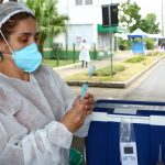 profissional de saúde usando máscara e epi maneja doses de vacina em drive-thru - vacinção de 60 anos na grande florianópolis