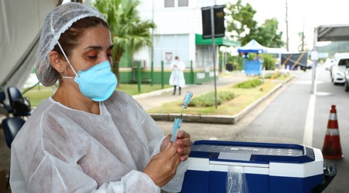 profissional de saúde usando máscara e epi maneja doses de vacina em drive-thru - vacinção de 60 anos na grande florianópolis