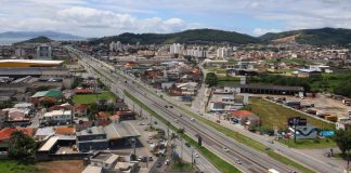 Vista de cima de Biguaçu, que faz aniversário nesta segunda-feira, é possível vem uma rodovia com casas, prédios e indústrias ao redor.