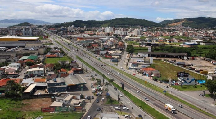 Vista de cima de Biguaçu, que faz aniversário nesta segunda-feira, é possível vem uma rodovia com casas, prédios e indústrias ao redor.