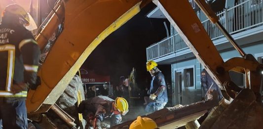 bombeiros usam retroescavadiera para procurar por mulher embaixo dos escombors do imóvel que explodiu