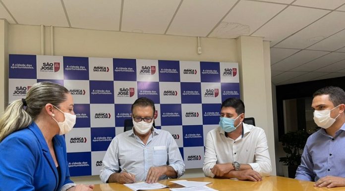 em uma mesa, o prefeito Orvino, a presidente da Câmara Méri Hang, o vice prefeito e o secretário da SUSP estão de máscara sentado em uma mesa com papeis sobre o projeto de lei do procedimento urbanístico de São José