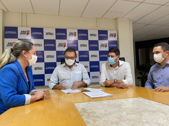 em uma mesa, o prefeito Orvino, a presidente da Câmara Méri Hang, o vice prefeito e o secretário da SUSP estão de máscara sentado em uma mesa com papeis sobre o projeto de lei do procedimento urbanístico de São José