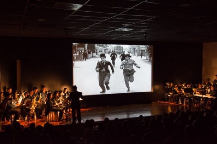 Um palco com artistas e uma tela com uma imagem de Chaplin. O governo de SC divulgou os critérios de seleção de projetos culturais na lei do mecenato