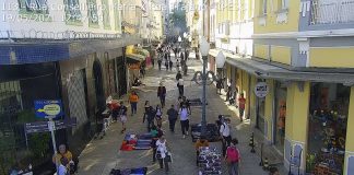 Câmera de monitoramento em rua no centro de florianópolis, com pessoas passando e comércio ambulante. a imagem ilustra matéria sobre o aumento no número de casos ativos de coronavírus no estado.