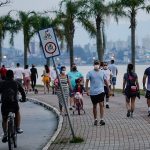 pessoas andando de máscara no calçadão da beira-mar em florianópolis - grande florianópolis