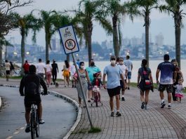 pessoas andando de máscara no calçadão da beira-mar em florianópolis - grande florianópolis