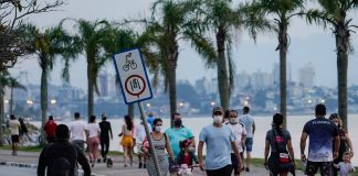 pessoas andando de máscara no calçadão da beira-mar em florianópolis - grande florianópolis