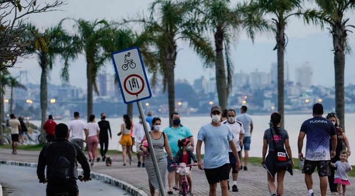 pessoas andando de máscara no calçadão da beira-mar em florianópolis - grande florianópolis