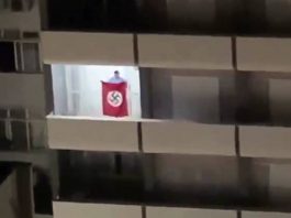 homem abana bandeira nazista em sacada de prédio