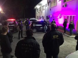 Operação de combate à pornografia infantojuvenil prende dois na capital Policiais civis estão em circulo e uniformizados, no cenário ainda aparecem carros da polícia, eles cumpriram mandados e prenderam dois homens na operação de combate à pornografia infantojuvenil em Florianópolis