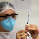 profissional de saúde retira dose de vacina de ampola com agulha - vacinação de pessoas com comorbidades em florianópolis