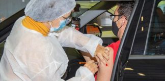 Vacinação nesta segunda-feira na Grande Florianópolis - profissional aplica dose no braço de homem dentro de carro