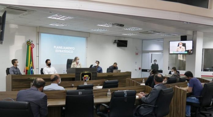 Do fundo da câmara de são josé é possível ver o telão em azul com escritas em branco identificando planejamento estratégico. Na mesa, a vereadora Méri Hang acompanhada de três homens, a sua frente outras pessoas acompanham a apresentação.