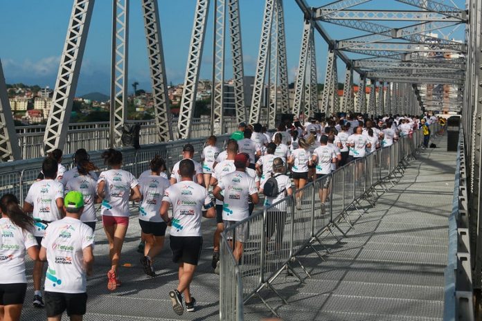 Corridas de rua liberadas: foto mostra grande quantidade de pessoas correndo sobre a ponte hercílio luz, vistas de costas