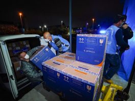 231 mil doses de vacinas serão distribuídas em SC nesta quinta; Janssen chega na próxima semana homens retirando de carro caixa de papelão com doses de vacina para distribuição