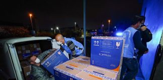 homens retirando de carro caixa de papelão com doses de vacina para distribuição