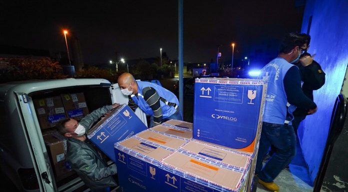 homens retirando de carro caixa de papelão com doses de vacina para distribuição