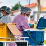 profissionais de saúd e de florianópolis trabalhando em ponto de vacinação e manejando caixas com doses de vacinas