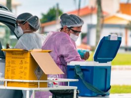 profissionais de saúd e de florianópolis trabalhando em ponto de vacinação e manejando caixas com doses de vacinas