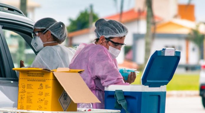 profissionais de saúd e de florianópolis trabalhando em ponto de vacinação e manejando caixas com doses de vacinas