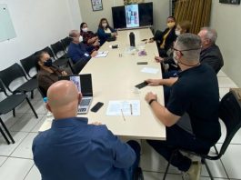 Em volta de uma mesa, nove pessoas estão reunidas e usando máscaras. A ONG e a prefeitura firmaram acordo para a cessão de um terreno para a horta comunitária do brejaru.