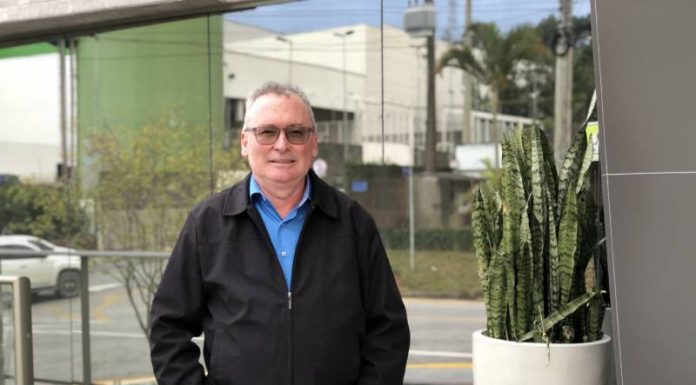 José Marciel neis posa com as mãos nos bolsos da calça, ele veste calça e jaqueta preta, além de uma camiseta azul. Ele usa óculos, tem cabelos grisalhos e pele branca. Neis será o novo presidente da Aemflo e CDL de São José.