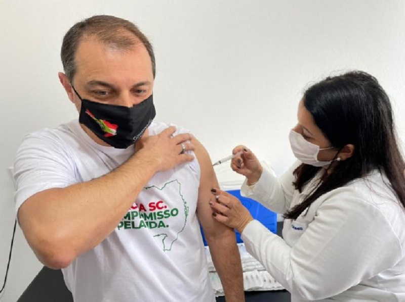 moisés usando máscara segura manga para receber dose de vacina no braço dada por enfermeira