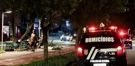 viatura da polícia civil com a inscrição "homicídios" passa por avenida com calçadão à noite -Crimes violentos em Santa Catarina