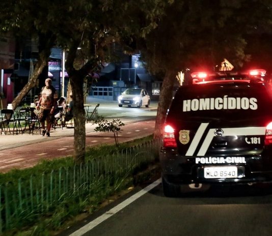 viatura da polícia civil com a inscrição "homicídios" passa por avenida com calçadão à noite -Crimes violentos em Santa Catarina