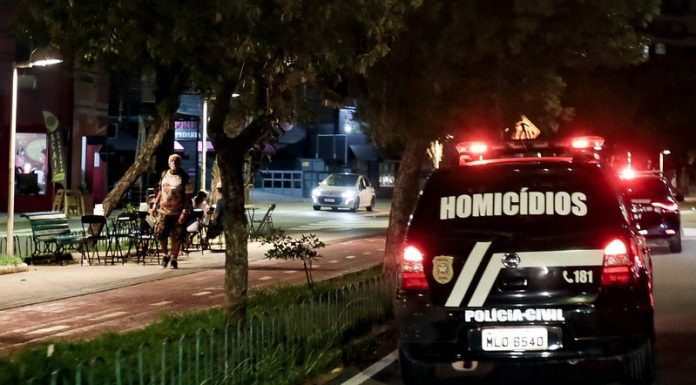 viatura da polícia civil com a inscrição "homicídios" passa por avenida com calçadão à noite -Crimes violentos em Santa Catarina