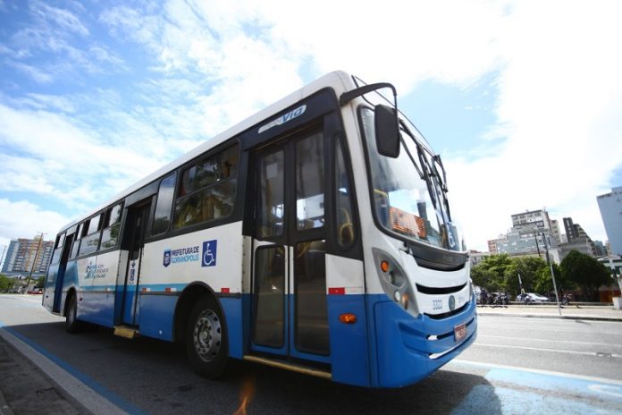 ônibus azul e branco na rua, com um céu azul ensolarado ao fundo. A partir de sábado, quem for se vacinar na capital terá passagem gratuita e dispensa do trabalho no dia da vacinação.