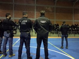 na deflagração da operação cova funda e cia policiais dentro de um ginásio: cinco em pé no meio da quadra e maioria sentada na arquibancada