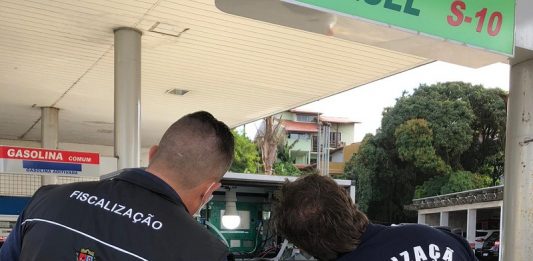 Postos de combustíveis são fiscalizados pelo Procon de São José Duas pessoas de cabelo curto estão de costas olhando para uma bomba de um posto de combustível. Um veste um colete escuro do Procon de São José e outro veste uma camiseta preta em que se lê fiscalização imetro/sc. A operação transparência lacrou bombas irregulares durante a fiscalização em postos de combustíveis de são josé.