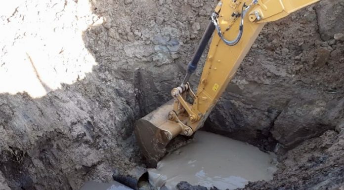 Seis bairros de Palhoça estão sem água há cinco dias - retroescavadeira cavando ao lado do cano rompido