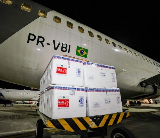 caixas de isopor em frente a um avião na chegada de parte do lote de 316 mil novas doses de vacinas contra covid para sc