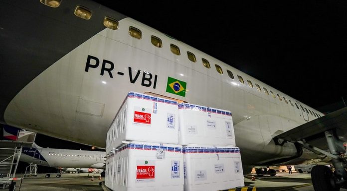 caixas de isopor em frente a um avião na chegada de parte do lote de 316 mil novas doses de vacinas contra covid para sc