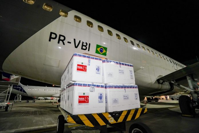 caixas de isopor em frente a um avião na chegada de parte do lote de 316 mil novas doses de vacinas contra covid para sc