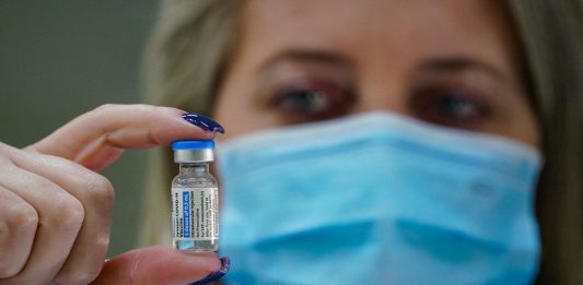 Santa Catarina tem 44,8% da população totalmente vacinada mulher usando máscara segura ampola de dose de vacina de covid