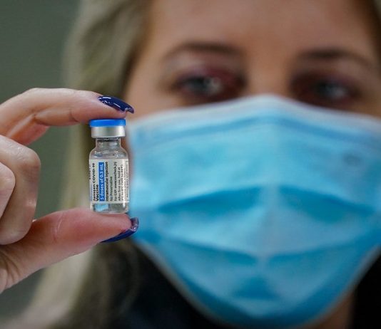 Santa Catarina tem 44,8% da população totalmente vacinada mulher usando máscara segura ampola de dose de vacina de covid
