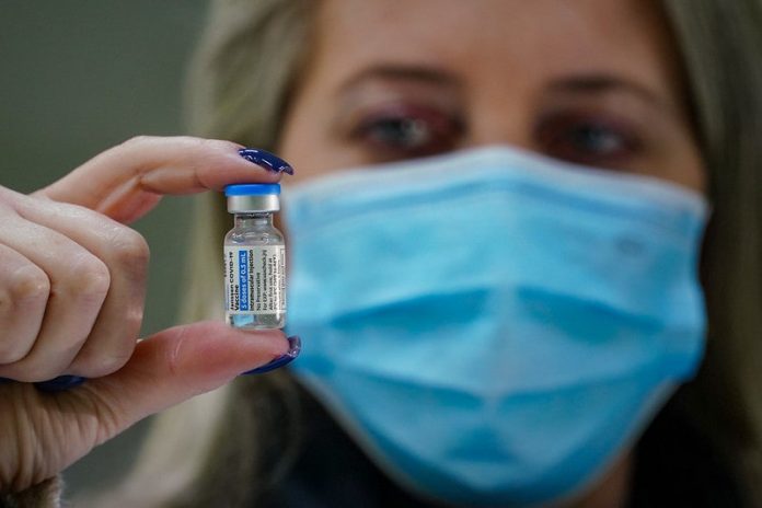 mulher usando máscara segura ampola de dose de vacina de covid